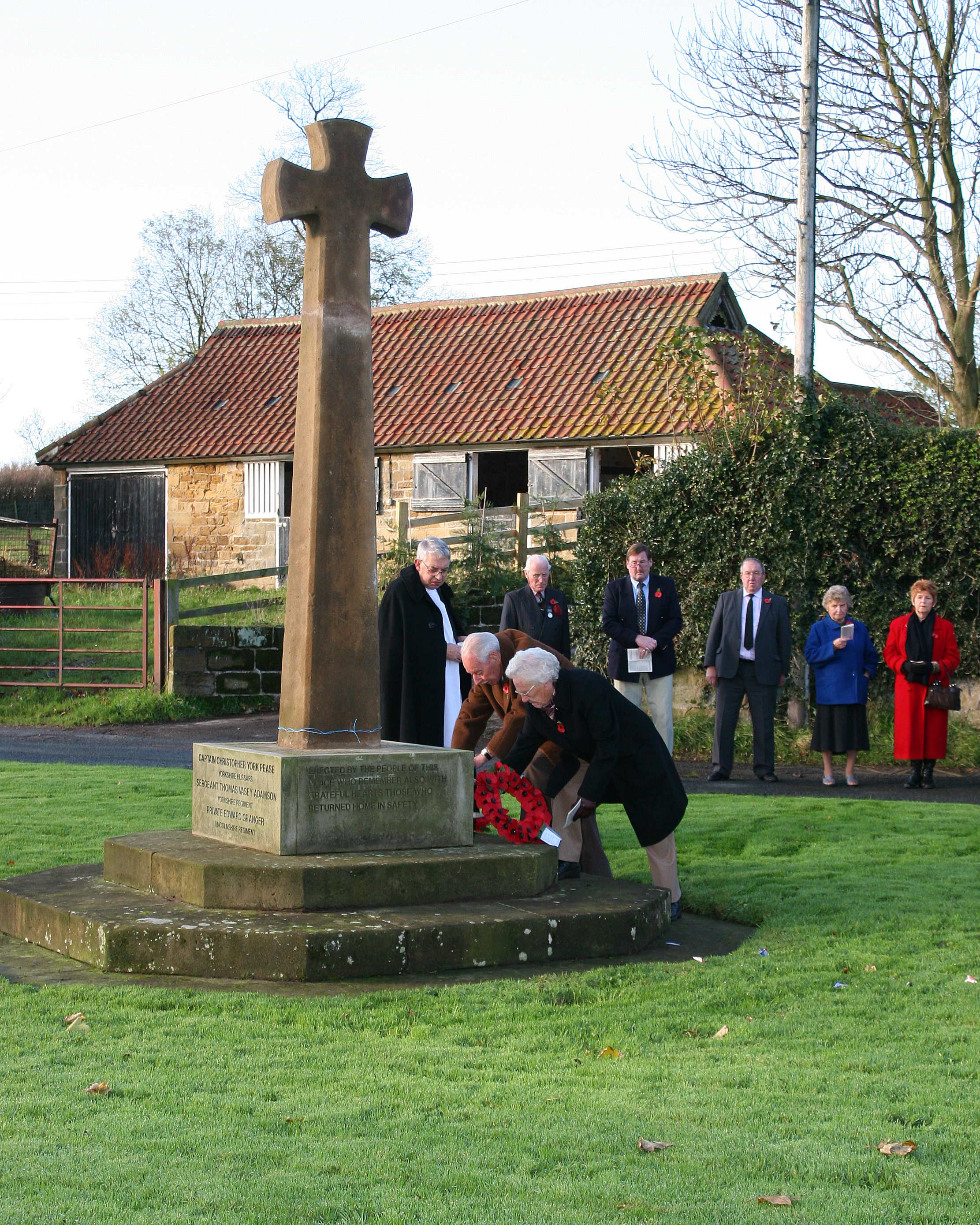 Members of the parish laying wreaths of red poppies at the base of the memorial